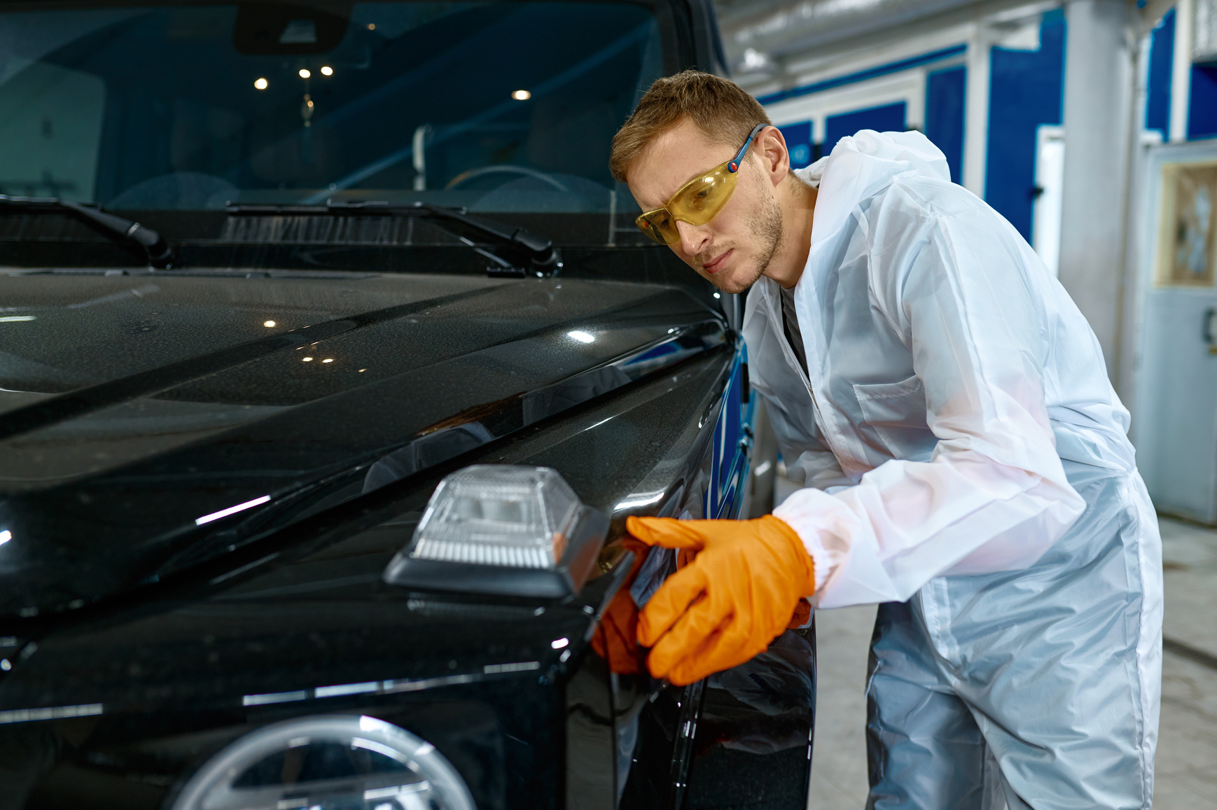 Serious Repairman Inspecting Painting Quality of Vehicle